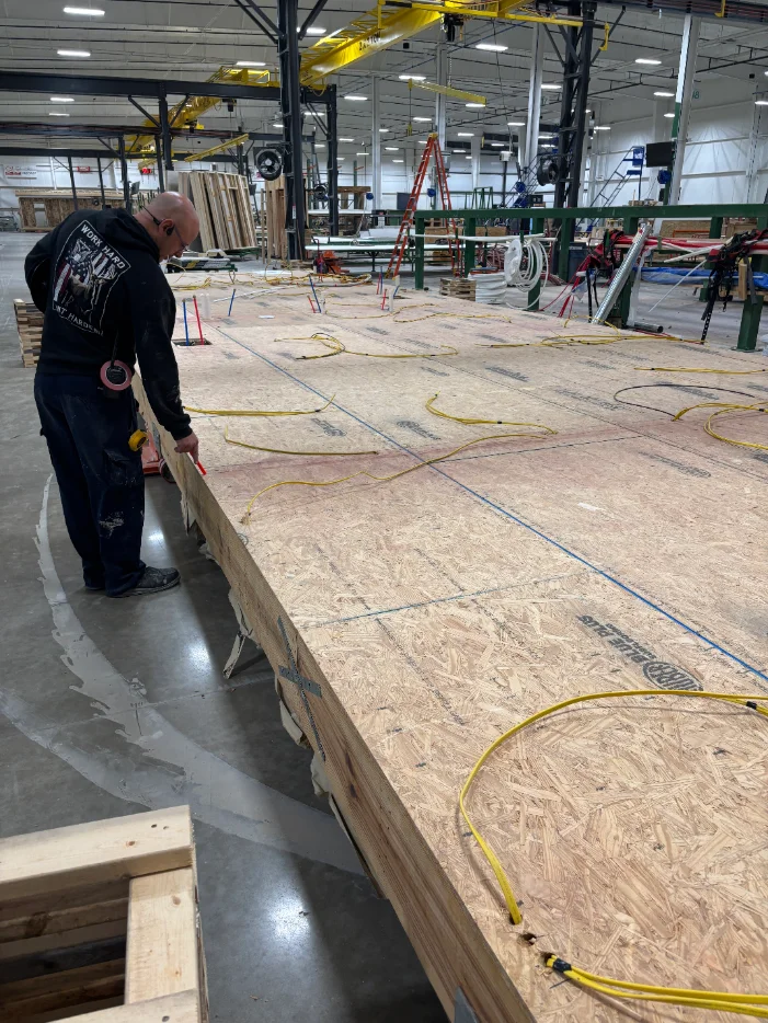 Worker measuring a completed modular floor deck on the factory line